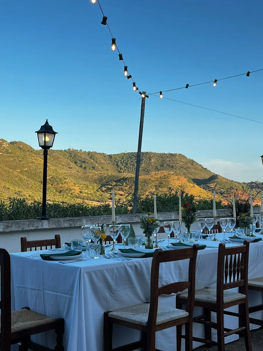 Mesa de banquete bajo guirnaldas con vistas a las montañas
