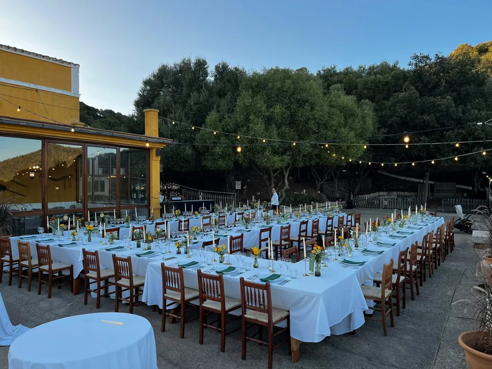 Mesas de banquete al aire libre bajo guirnaldas de luces